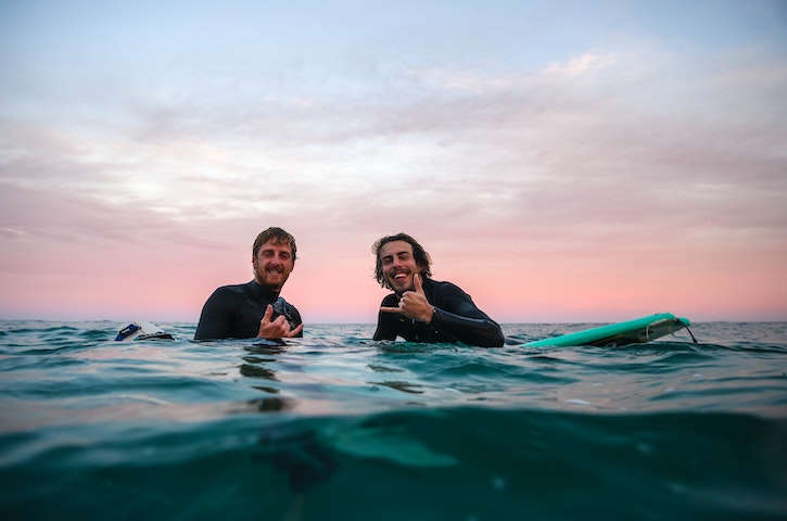 Two surfer in the water smiling and having a great time