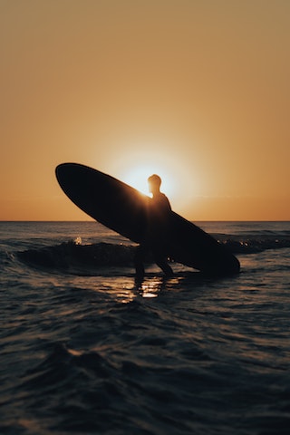 Surfer leaving the water enjoying the sunset